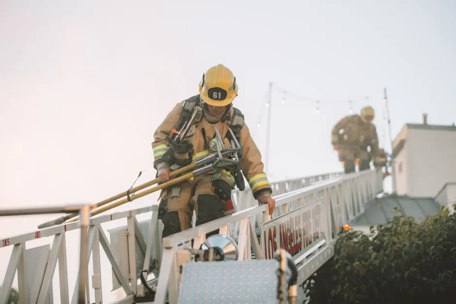 Firefighters in protective gear climbing down a ladder during a rescue operation. Teamwork in action.